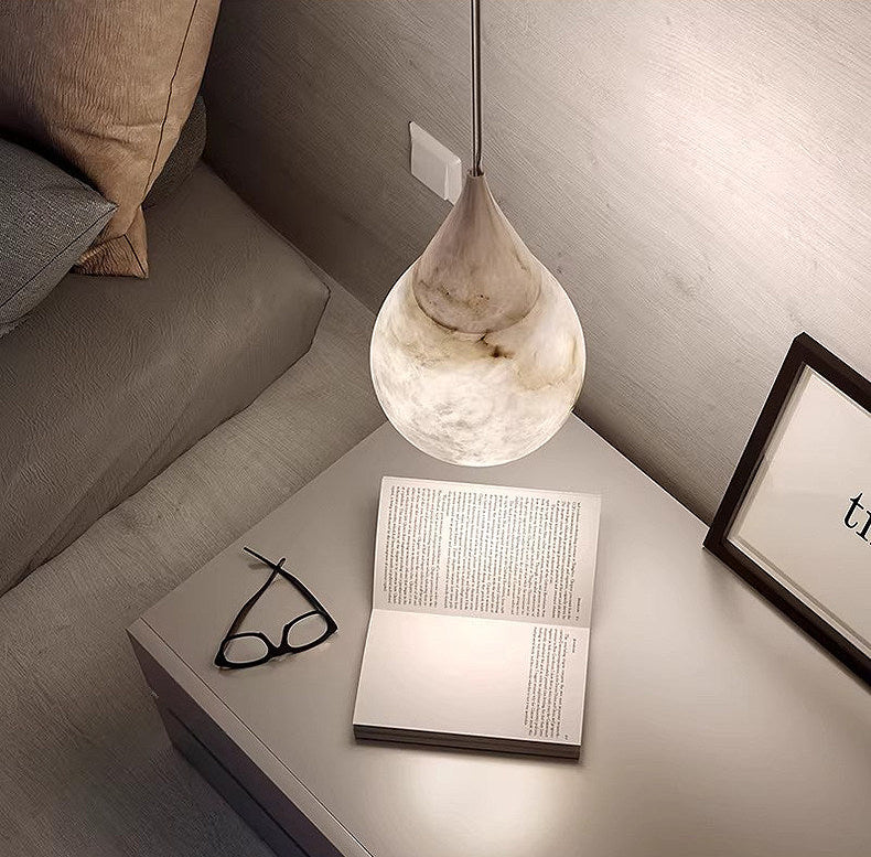 Lit Tova teardrop alabaster pendant lamp hanging above bedside table minimalist bedroom