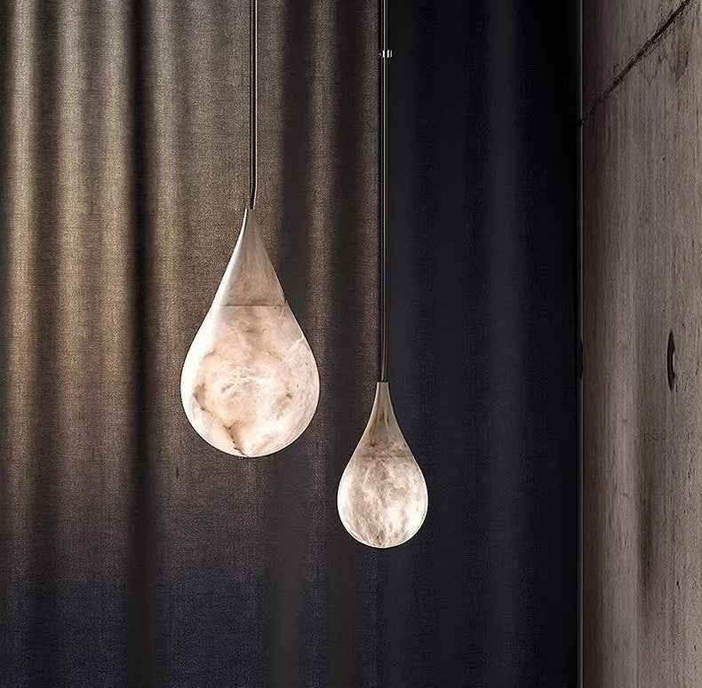 Two glowing Tova teardrop alabaster pendant lights against dark curtain interior