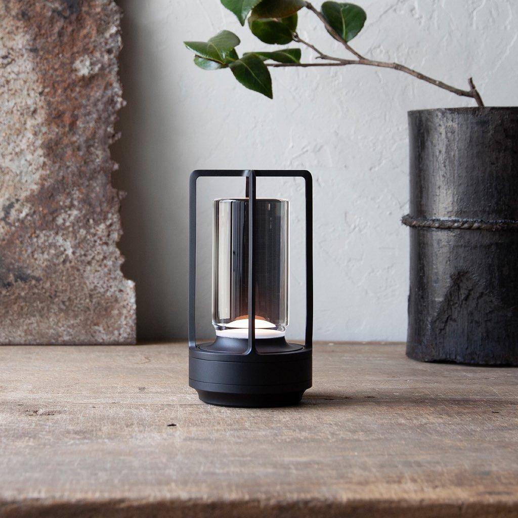 Black Turn Plus rechargeable table lamp placed on aged wooden table with plant decor