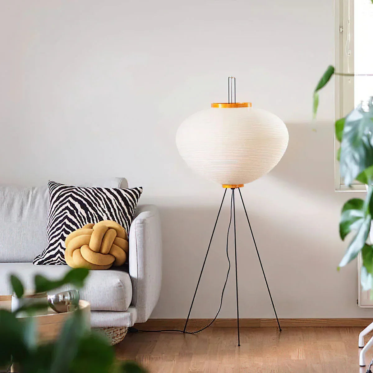 Akari 10A 14A Paper Floor Lamp glowing beside sofa and fresh green houseplant