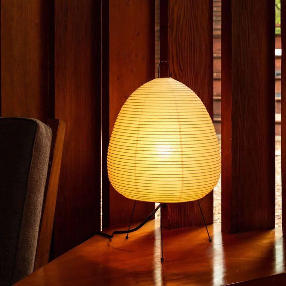 Akari Paper 1A Table Lamp warm light beside books dark wood furniture