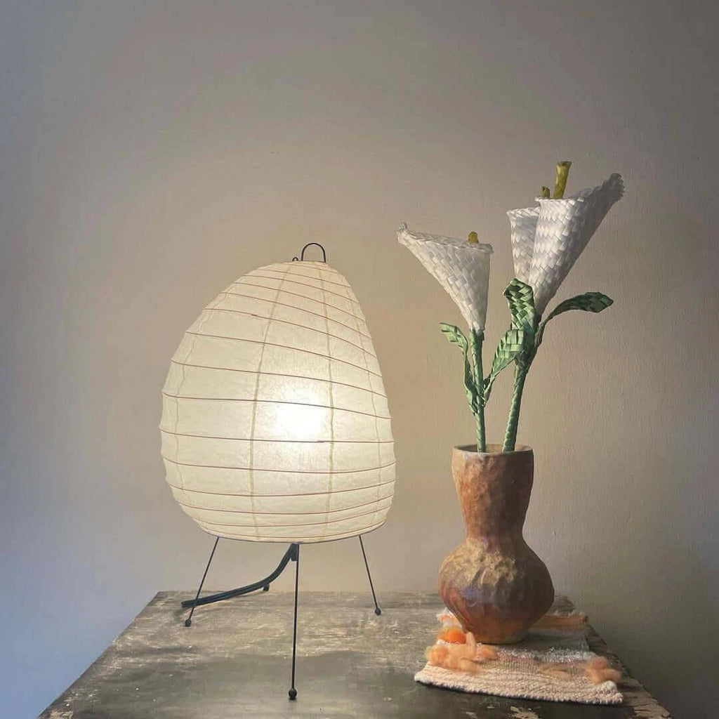 Illuminated Modern Tripod Table Lamp Next to Ceramic Vase