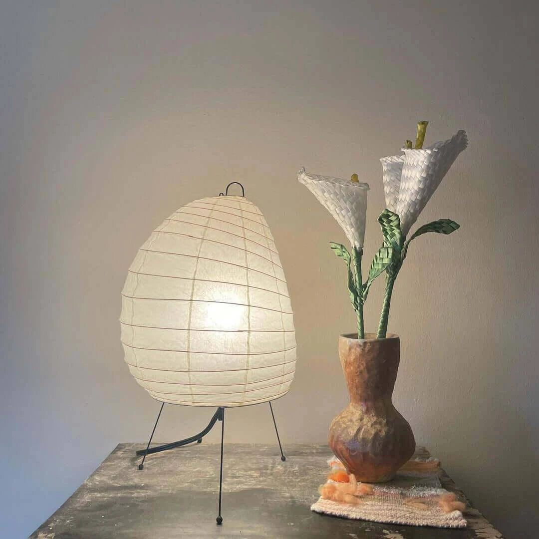 Illuminated Modern Tripod Table Lamp Next to Ceramic Vase