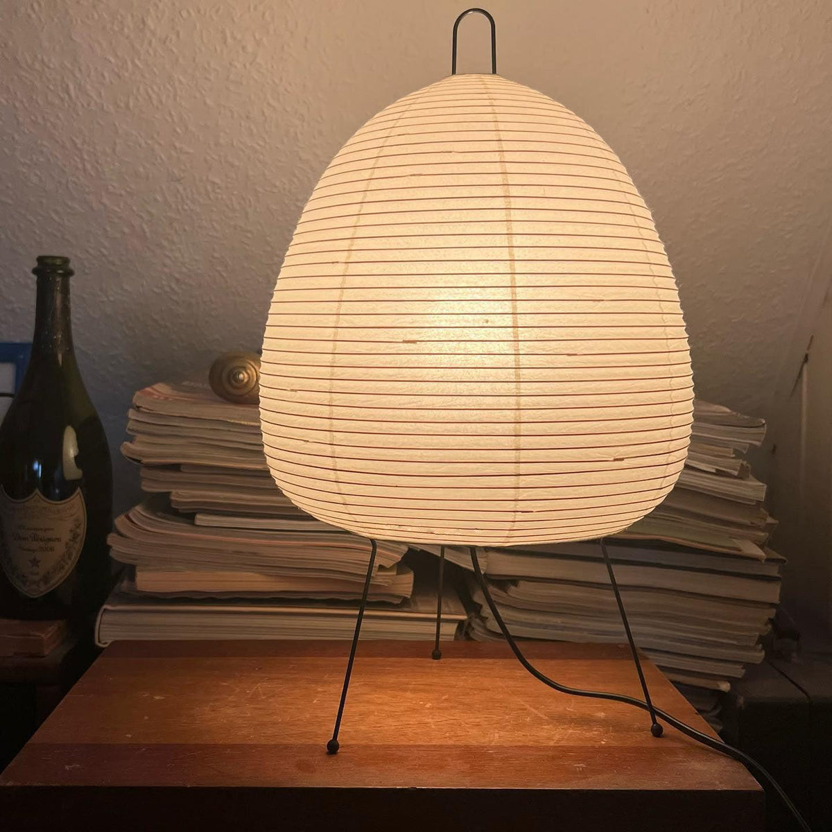 Warm Akari Paper 1A Table Lamp on rustic wooden table beside wine bottles