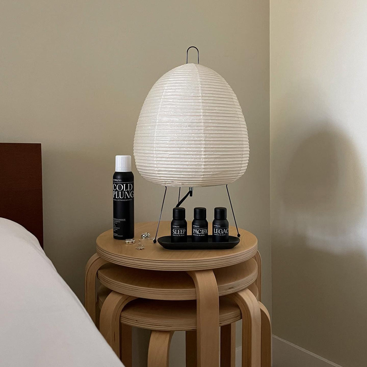 Unlit Akari Paper 1A Table Lamp atop wooden stool beside skincare decor