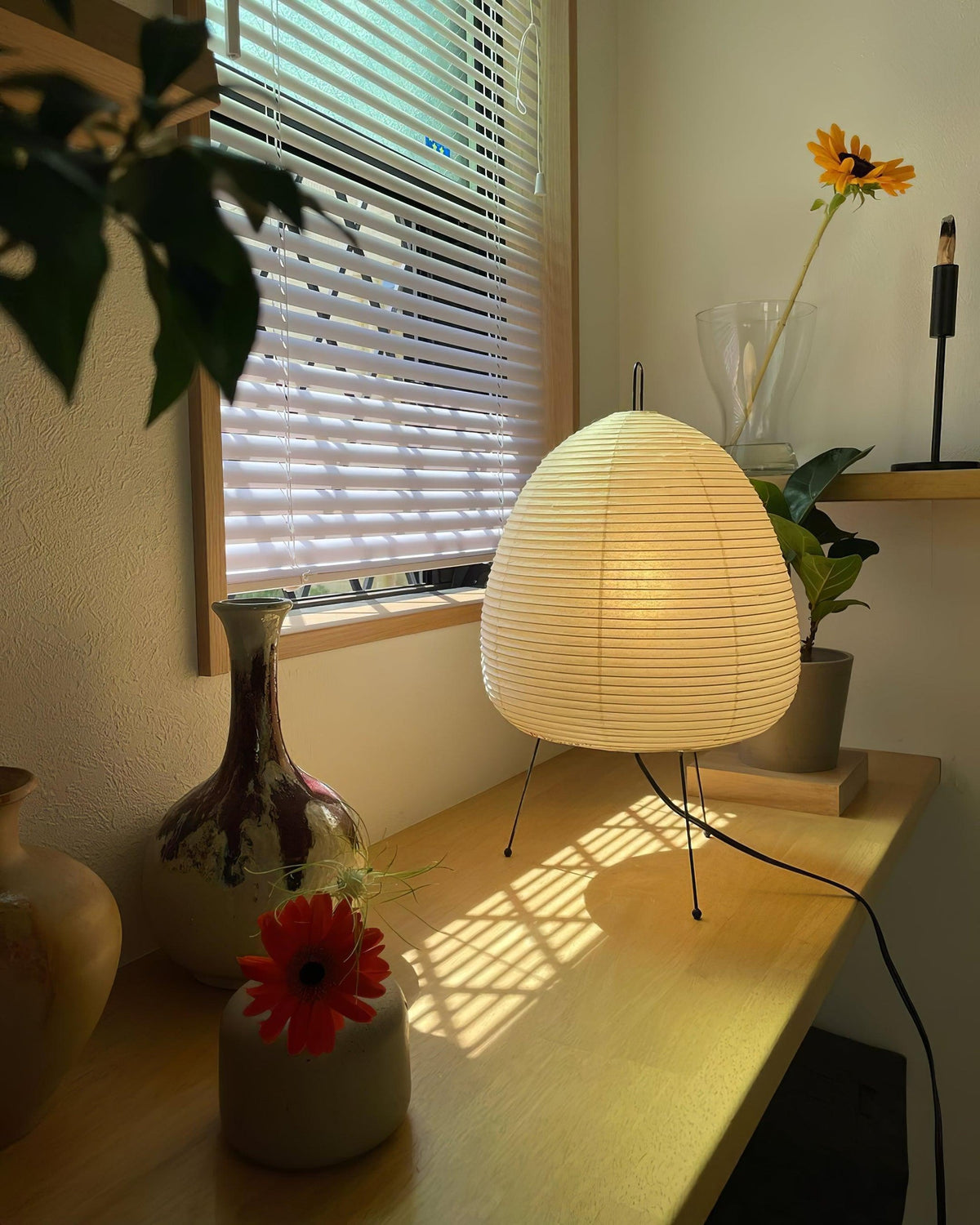 Akari Paper 1A Table Lamp glowing on window side wooden console table