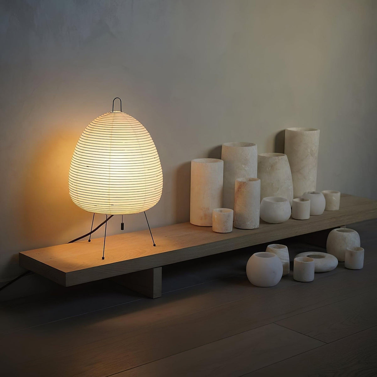 Akari Paper 1A Table Lamp glowing on display shelf with pottery decor