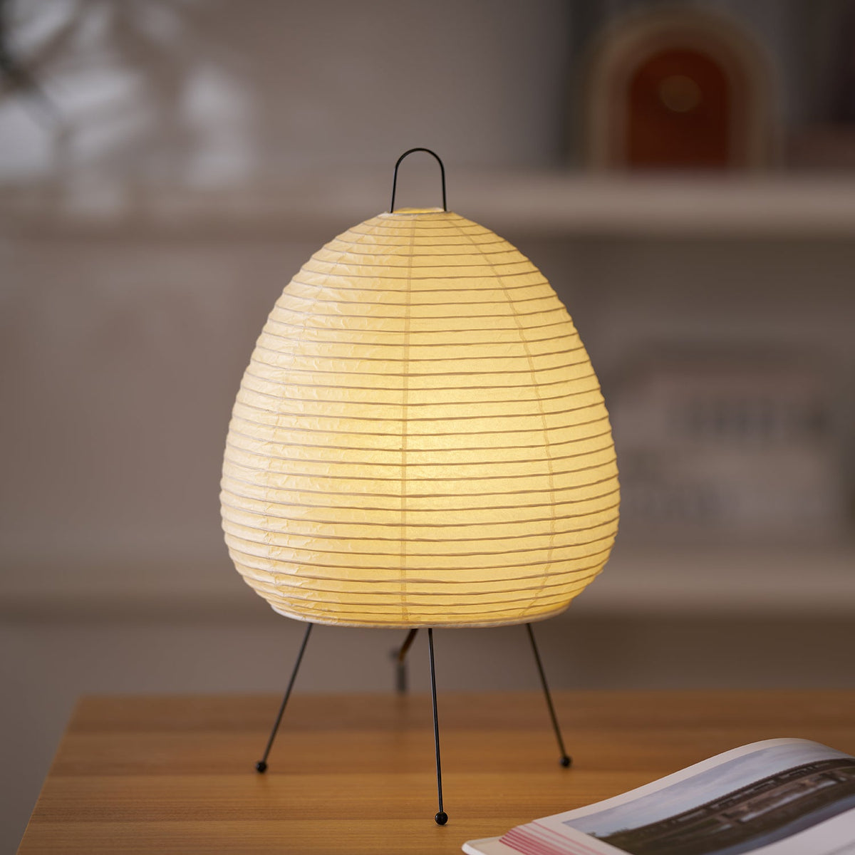 Akari Paper 1A Table Lamp standing on wooden desk near bookshelf