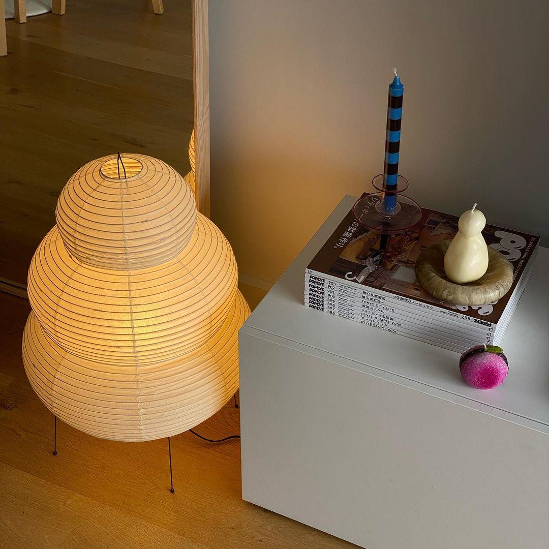 Warm lit Akari Paper 25N Table Lamp placed on side table minimalist decor corner