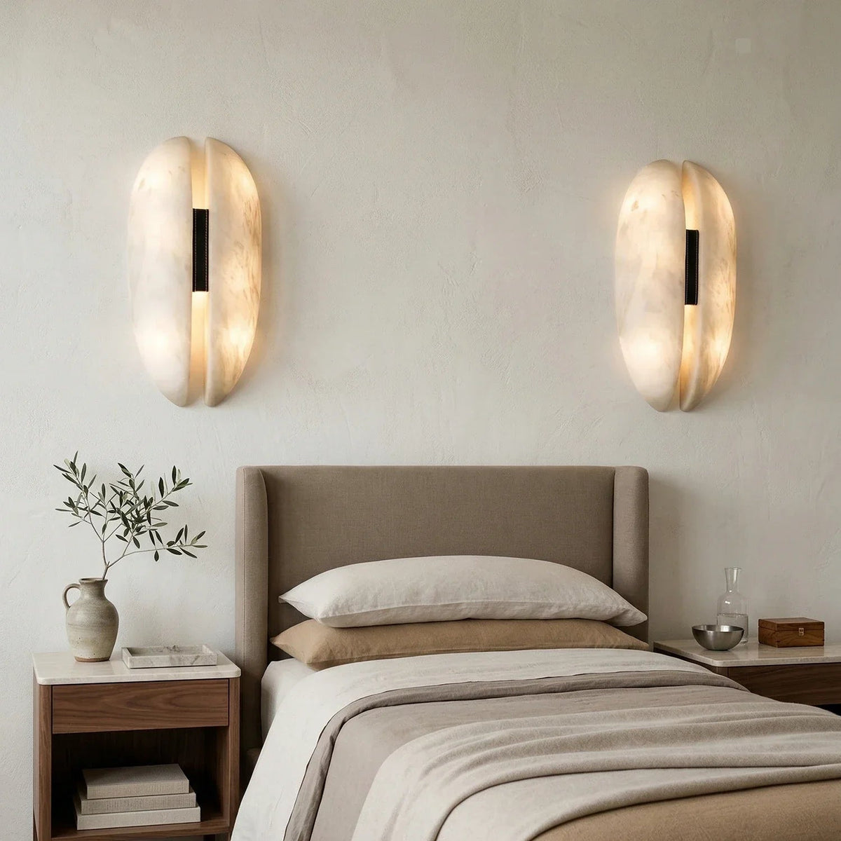 Pair of illuminated alabaster veil wall lights mounted above bedroom bedside table