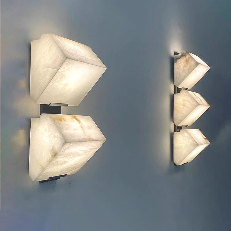Pairs of tiered alabaster wall sconces mounted on muted blue interior wall