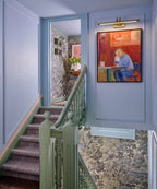 Modern Brass Wall Sconce Lighting Up Hallway Artwork