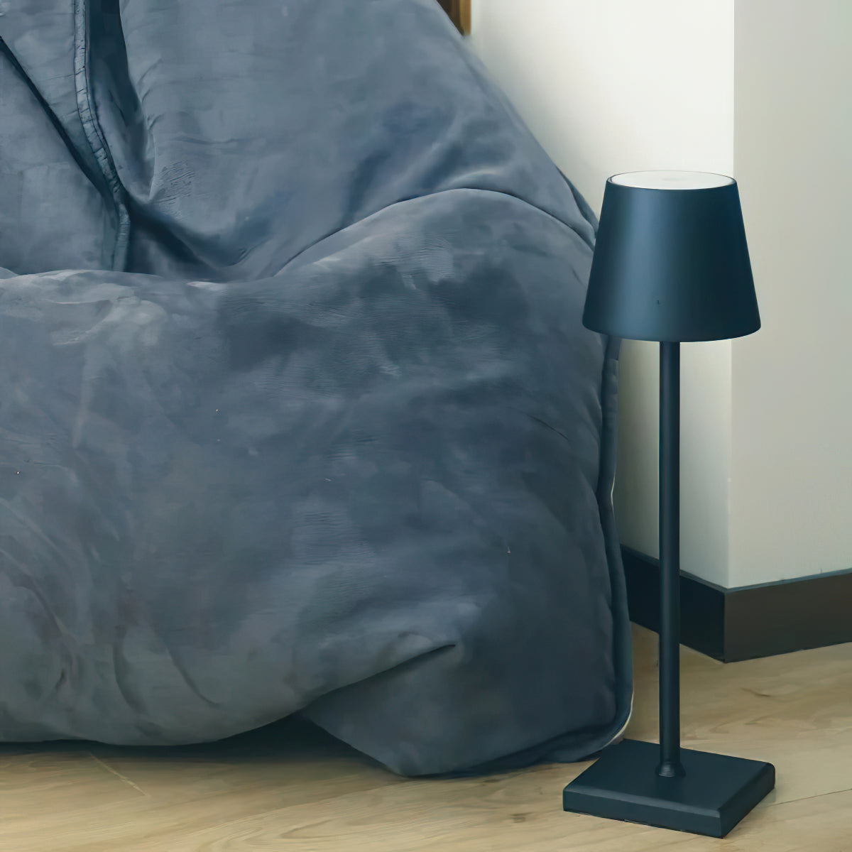 Black Apex rechargeable lamp standing beside grey fabric sofa casual living area