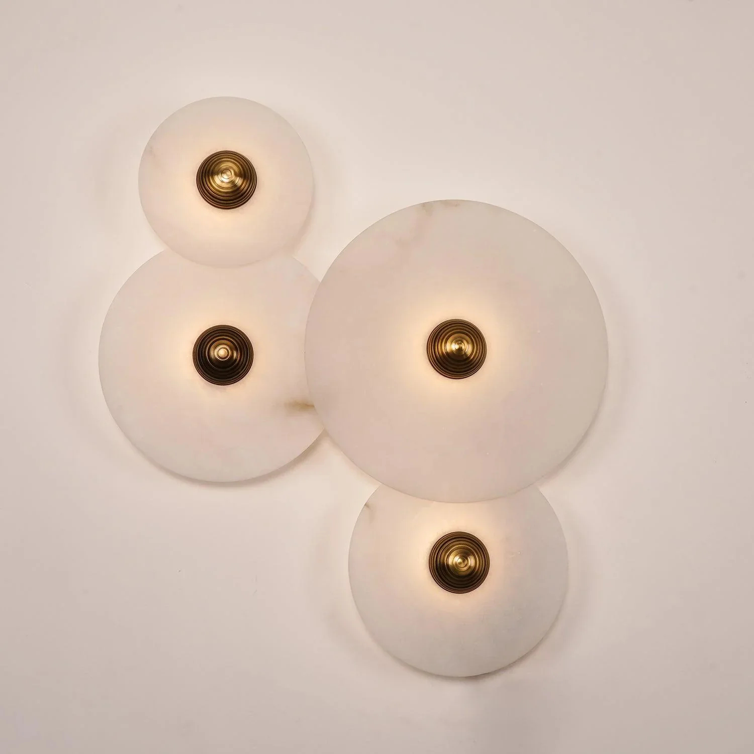 Two overlapping lit Solaris Stone Disc Wall Lamps alabaster and brass fixture