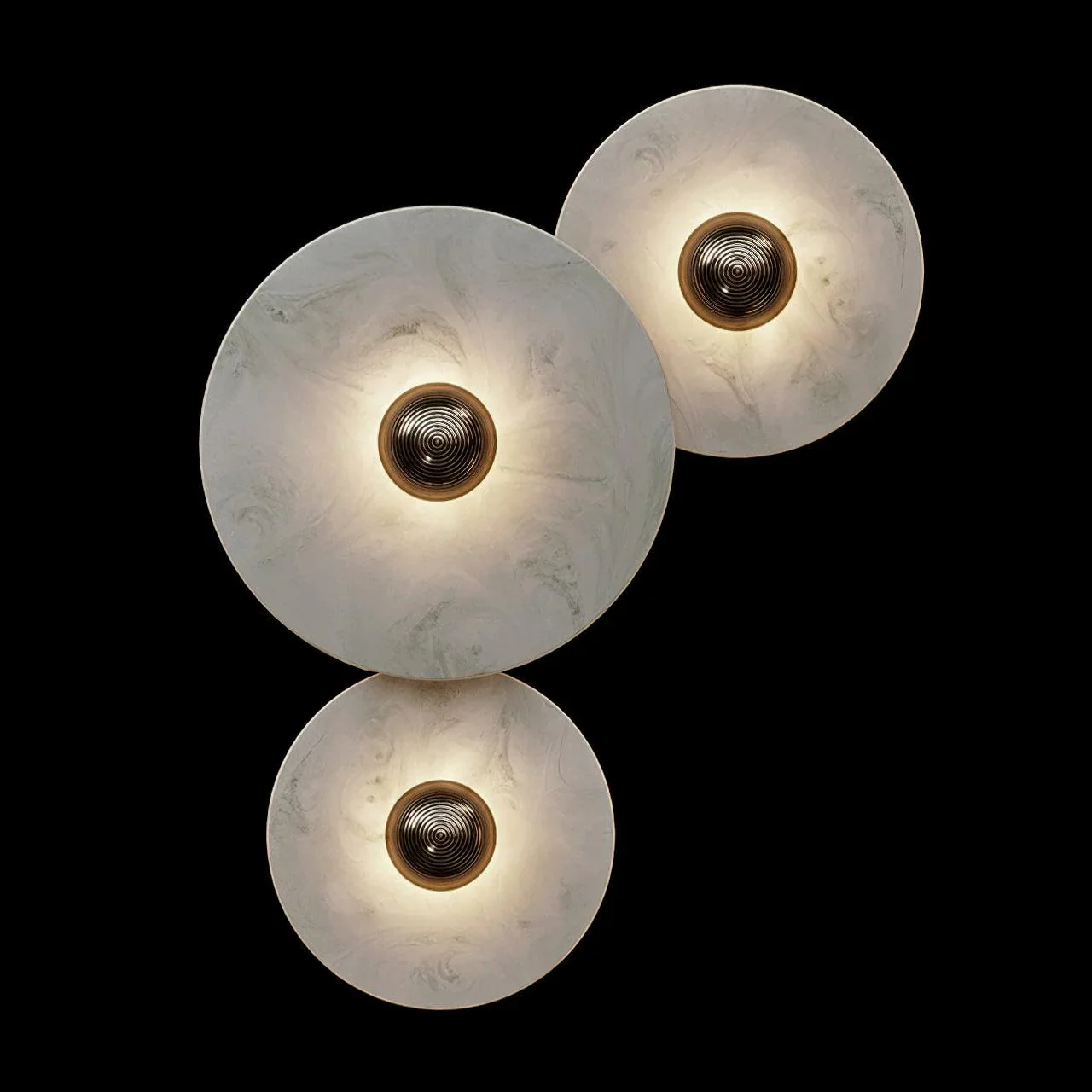 Three layered Solaris alabaster disc wall lights with warm glowing bulbs