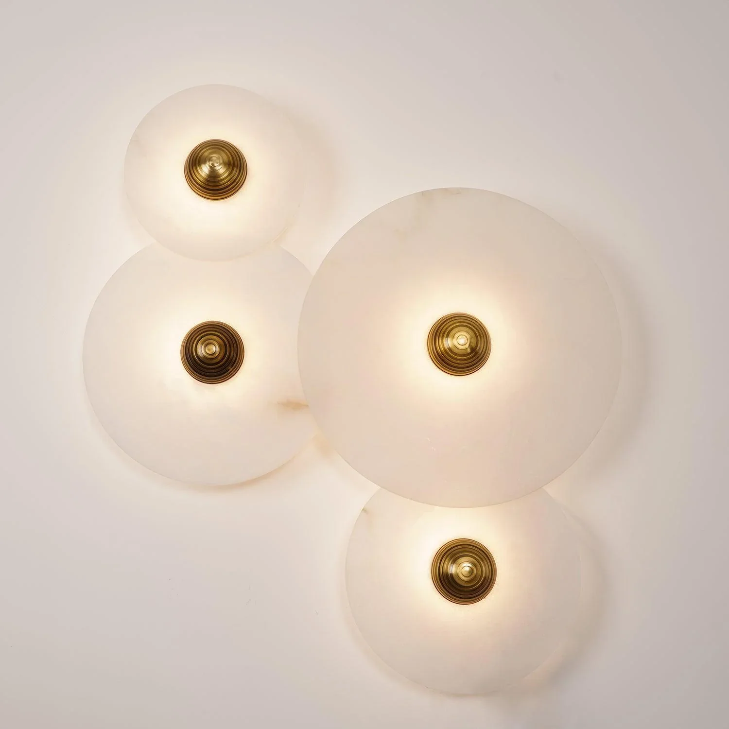 Three lit Solaris round alabaster sconces grouped together on interior wall