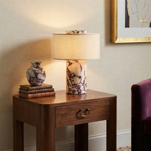 Lit Aurie marble table lamp placed on vintage wooden sideboard warm neutral living room interior