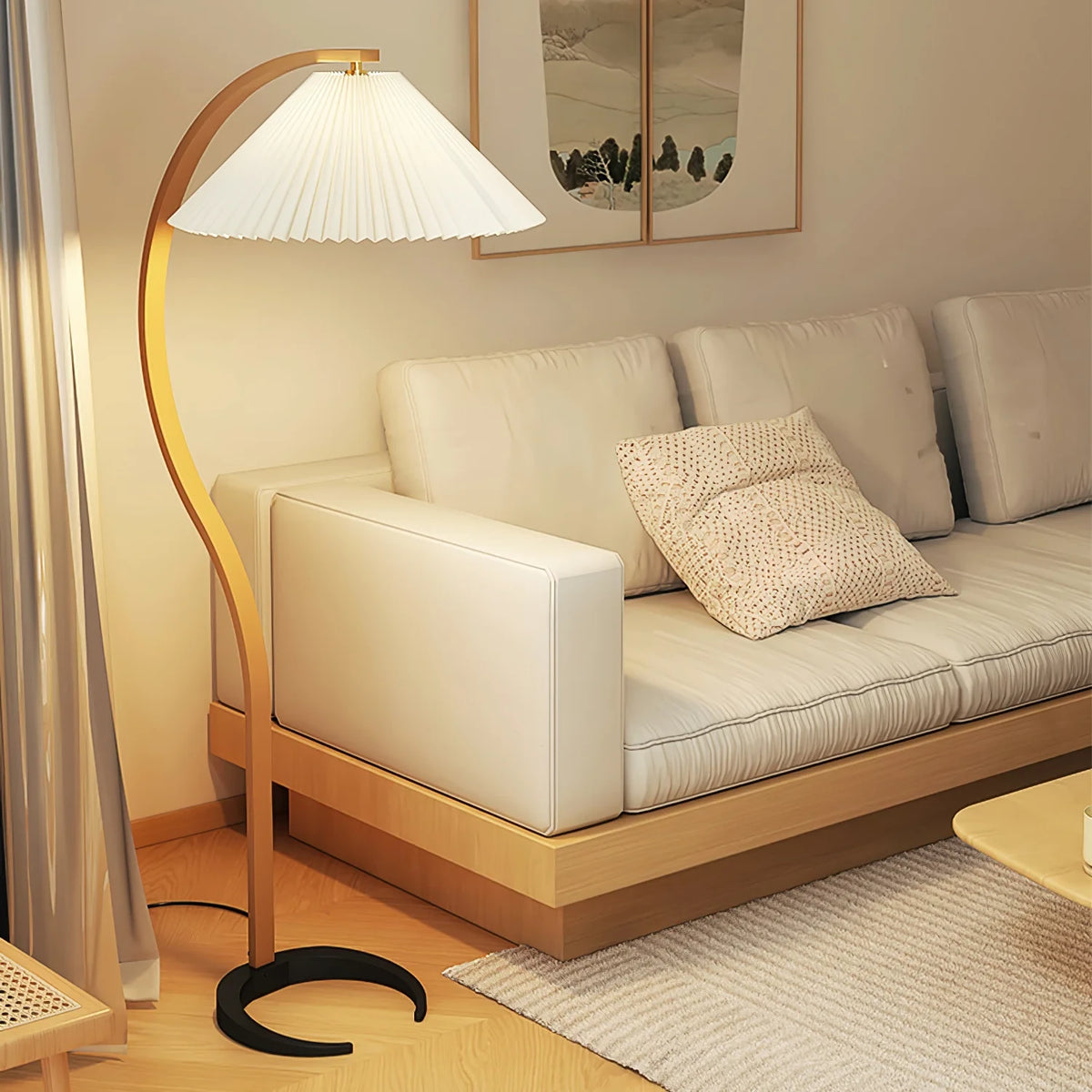 Caprani Floor Lamp light wood curved arm with white pleated shade, standing beside cream sofa in minimalist japanese style living room