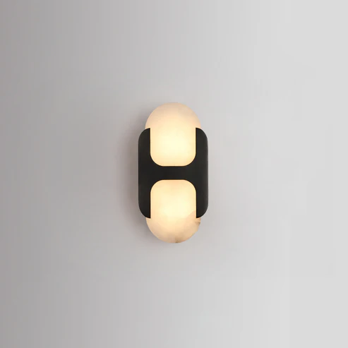 Black frame Capsule alabaster sconce illuminated mounted on pale neutral interior wall