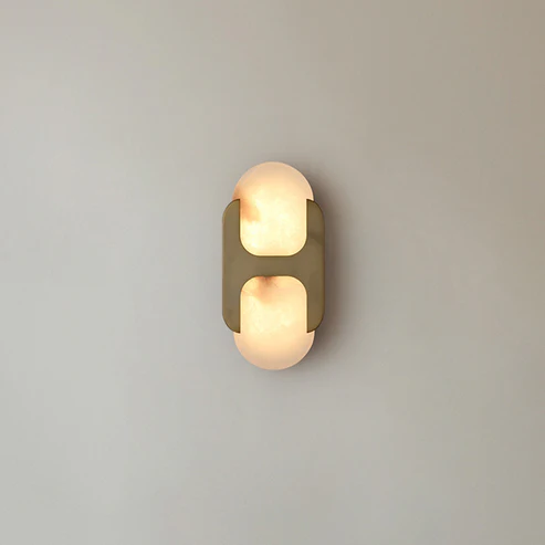 Warm light Capsule alabaster wall sconce brass mounted on light grey smooth wall