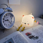 Cute Sleeping Cat Night Light Over Open Book and Alarm Clock