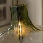 Close Up View of Illuminated Green Wave Art Glass Neck and Internal Light Glow on Dark Background