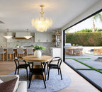 Gold Feather Glass Chandelier above a dining table beside large windows