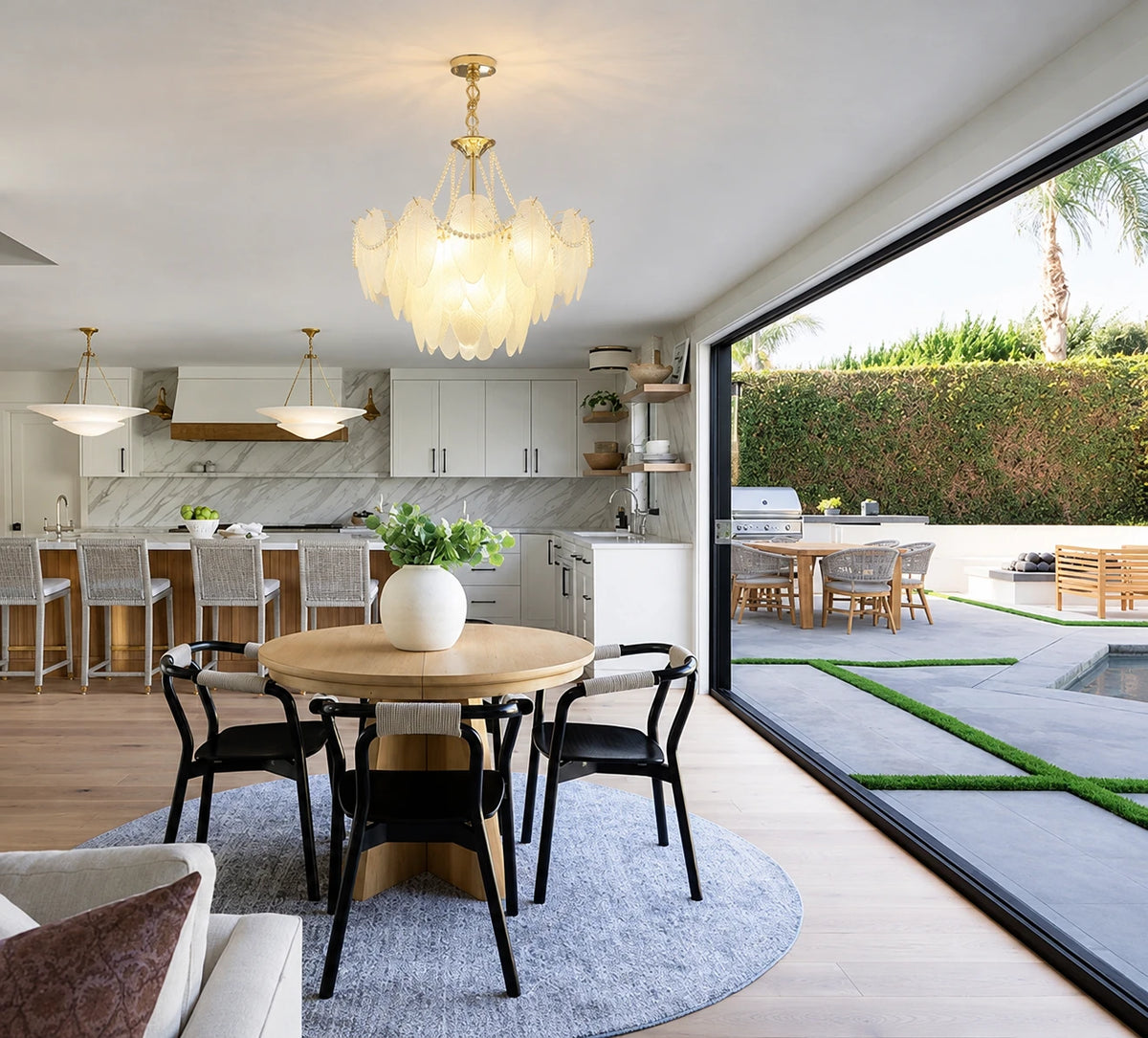 Gold Feather Glass Chandelier above a dining table beside large windows