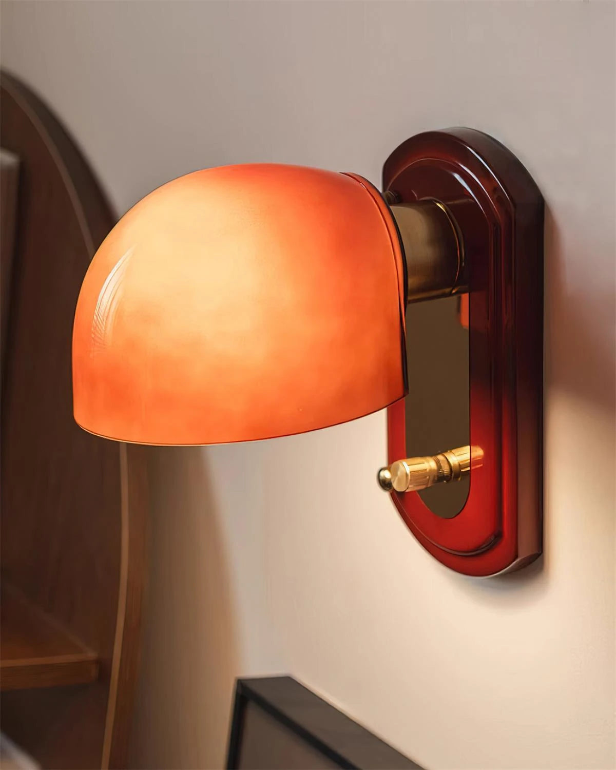 Vintage Orange Dome Wall Sconce Mounted Beside Wooden Bookshelf