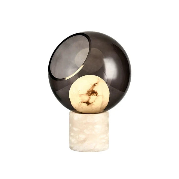 Modern Marble Base and Smoked Grey Cut-Sphere Art Glass Table Lamp with Warm Light on Pure White Background