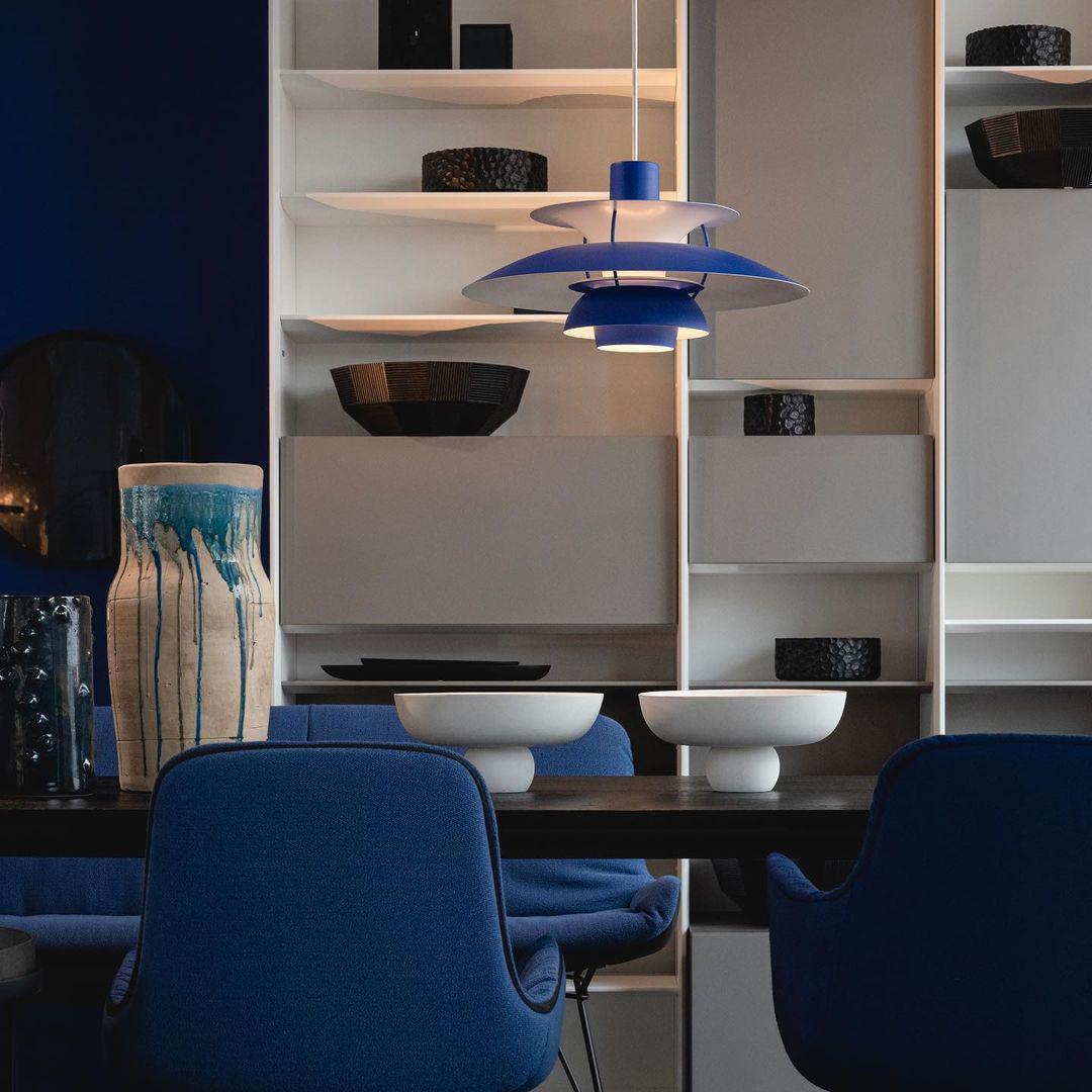 Blue PH 5 pendant lamp suspended above blue upholstered chairs modern dining space