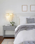 Modern Brass Frosted White Feather Wall Sconce with Pearl Strand in Bedroom Setting