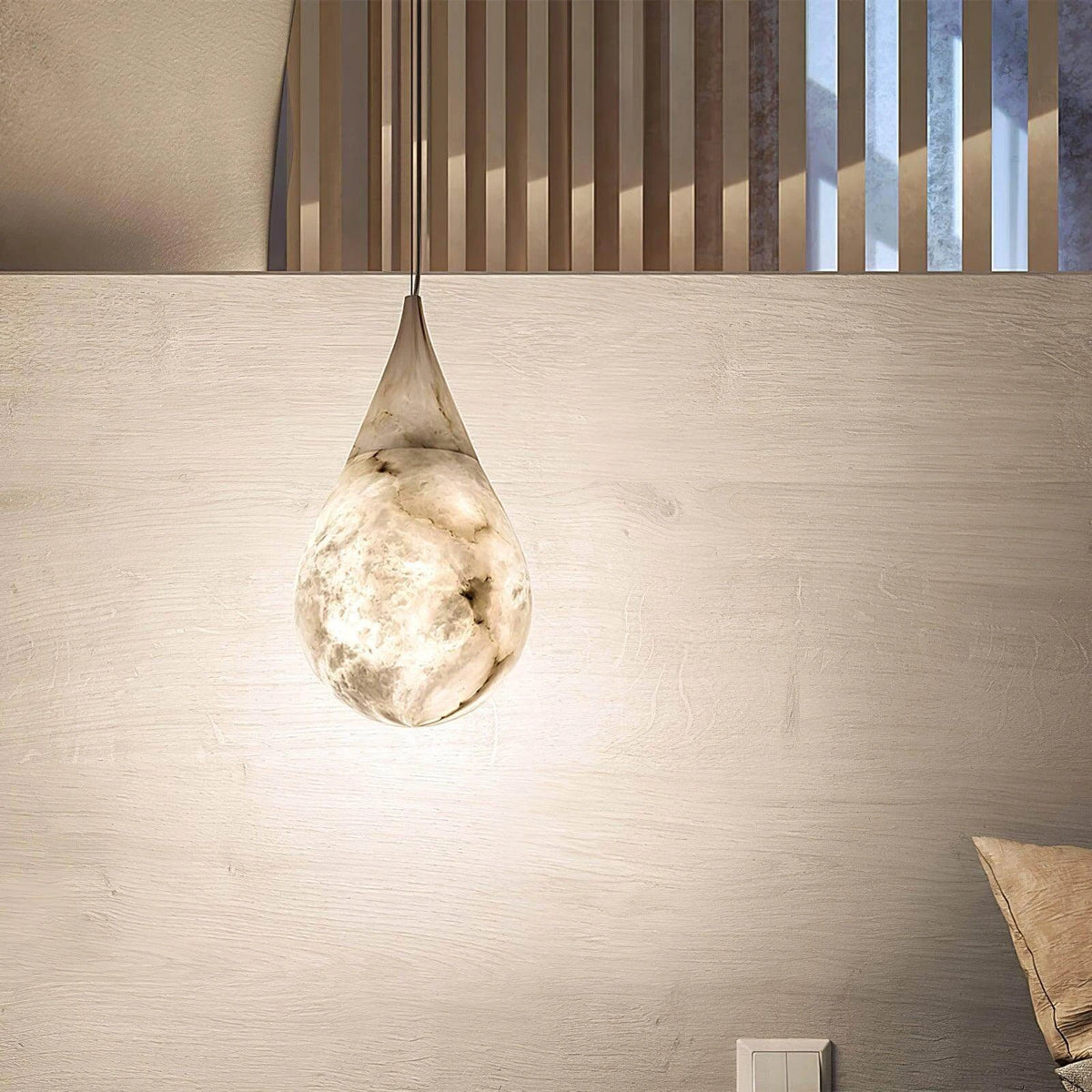 Illuminated Modern Natural Marble Teardrop Pendant Light Against Wooden Slatted Wall