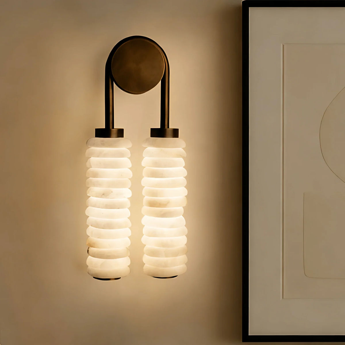 Unlit twin ribbed alabaster wall sconce with aged brass fixture on plain taupe wall