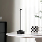 Verve brass wireless table lamp glowing softly against pale plaster wall