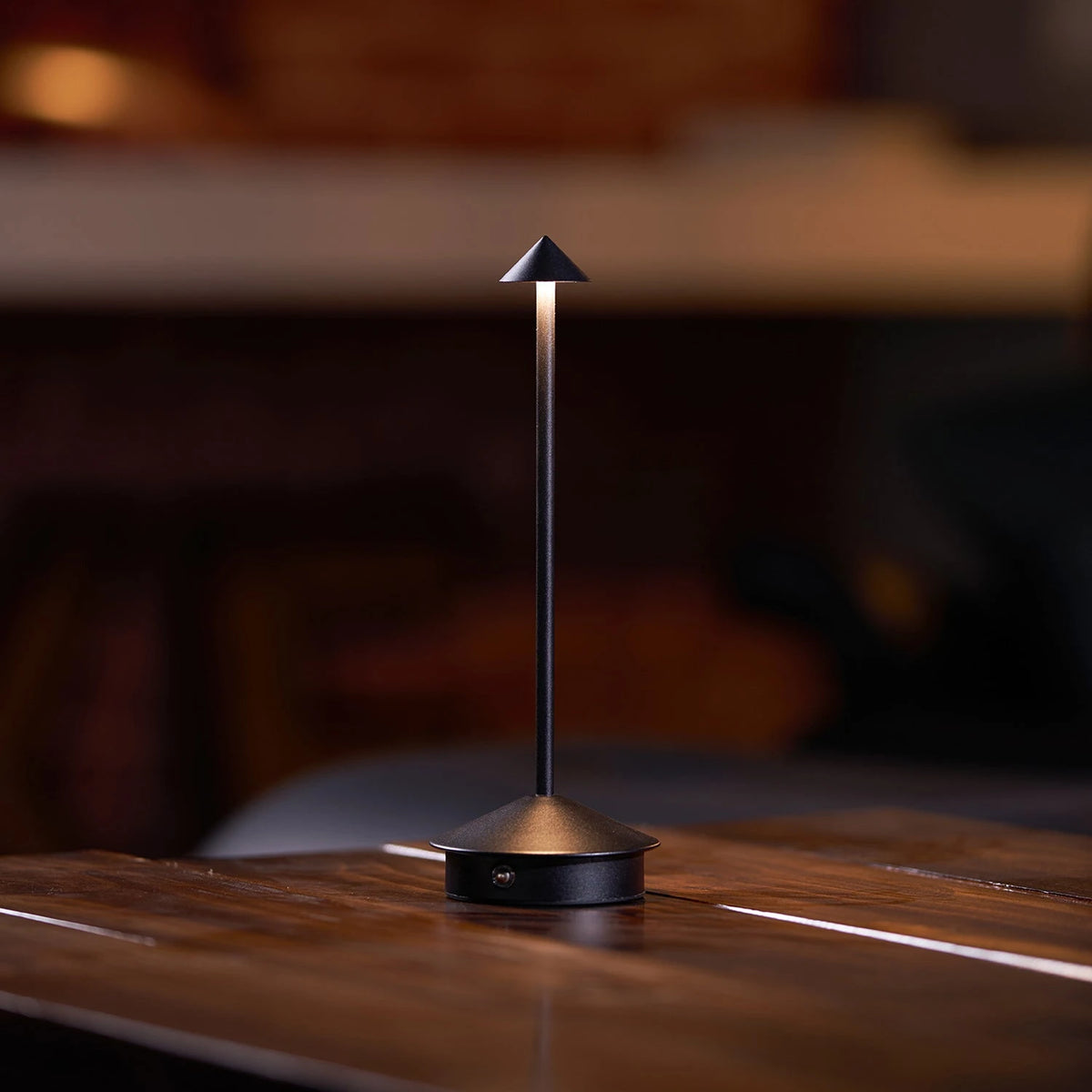 Dark bronze Verve wireless lamp sitting on open book reading nook interior shot