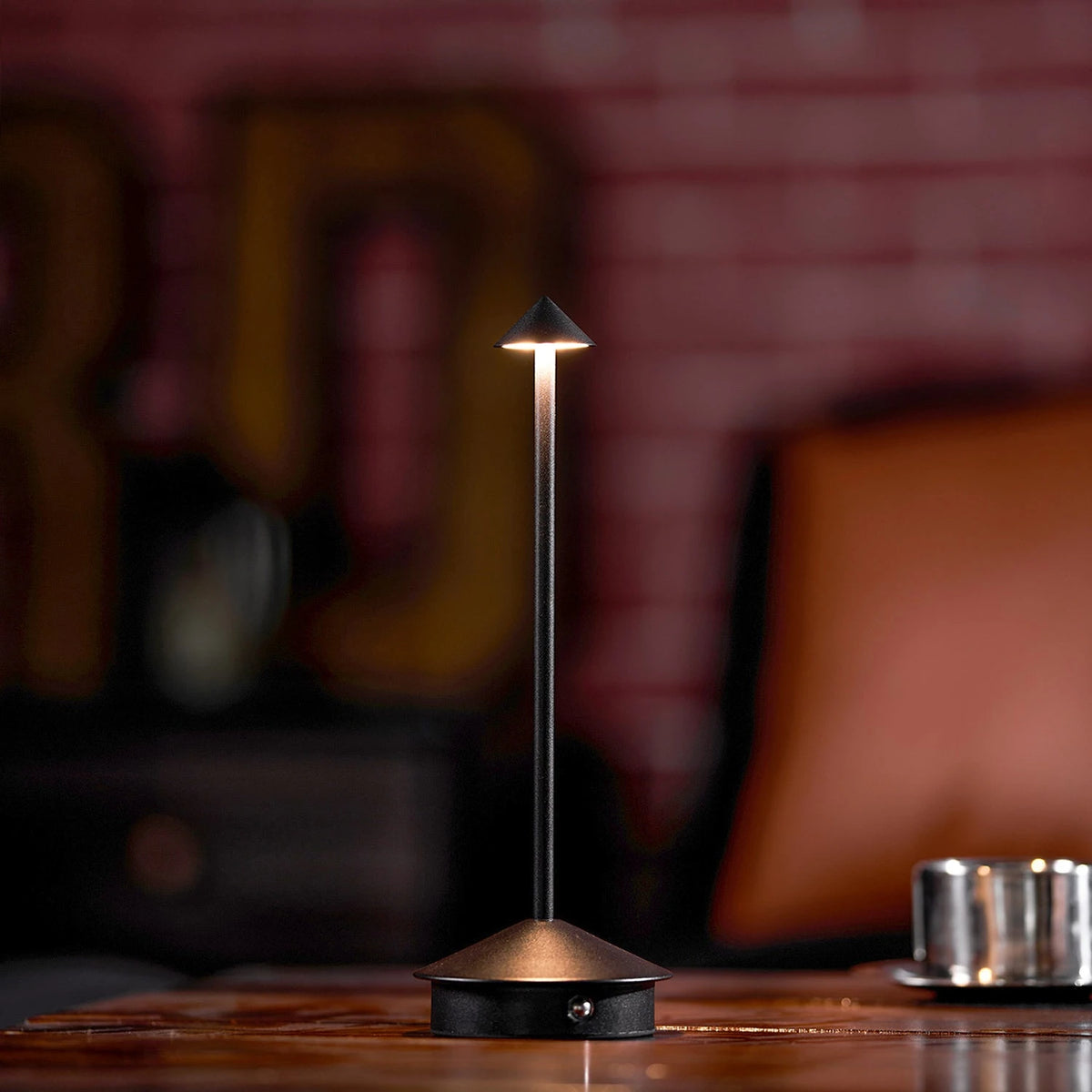 Black Verve cordless desk lamp illuminated on wooden home office worktop